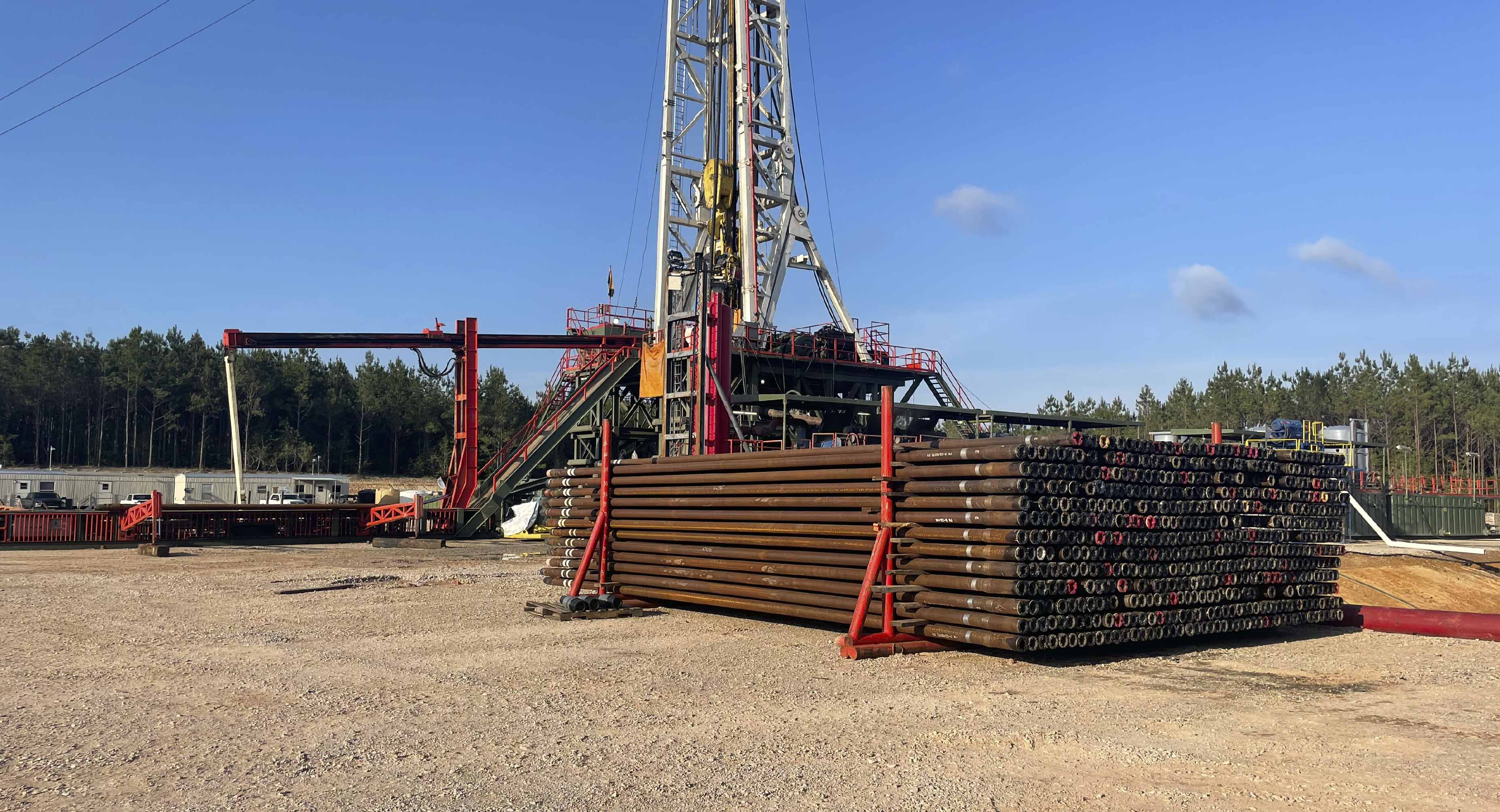 Stacked drill pipe and oil rig at active worksite in North Louisiana providing drilling support, pipe handling, and oilfield logistics services.