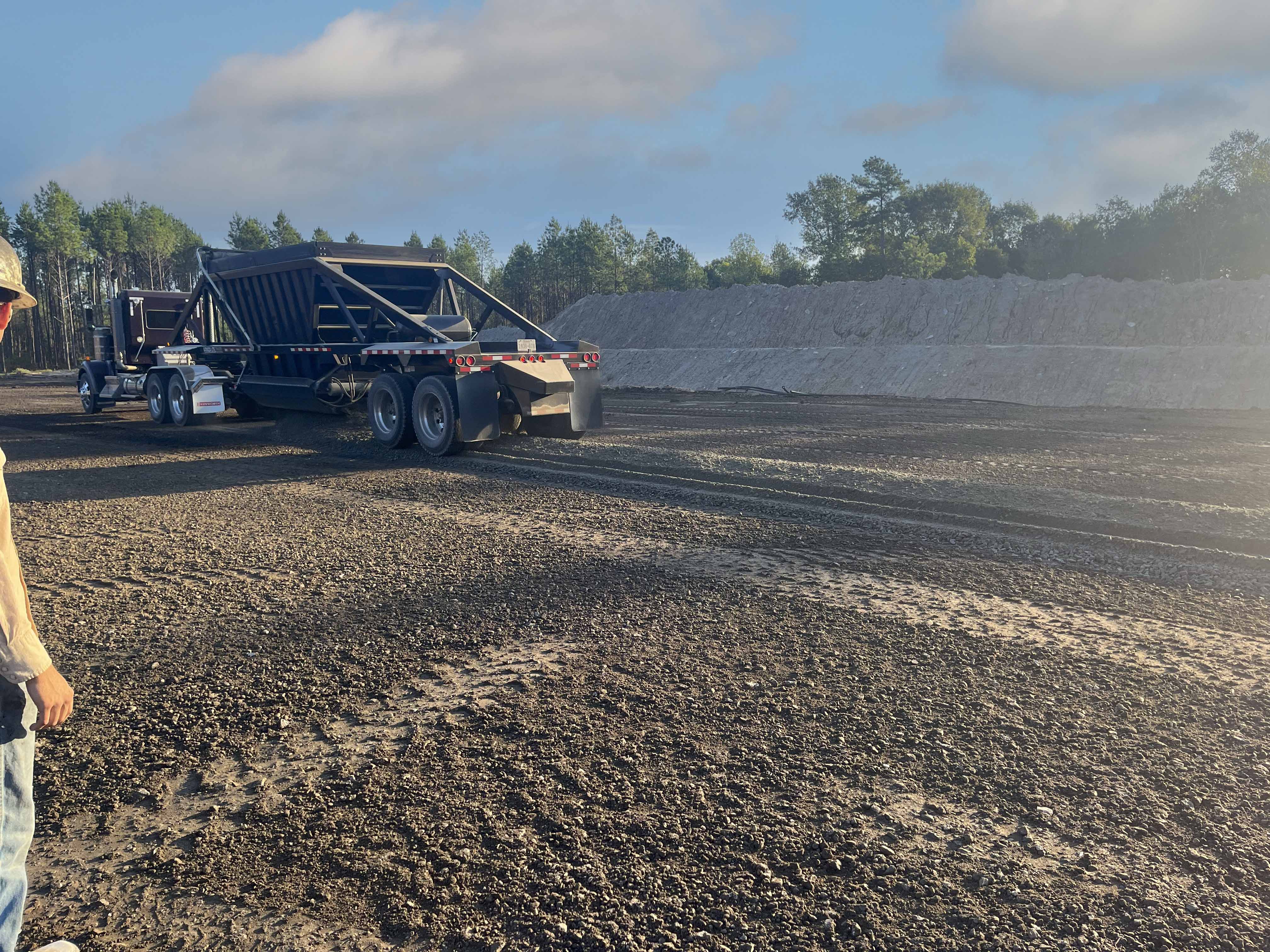 Dump truck hauling material at oilfield construction site in South Arkansas for site preparation services