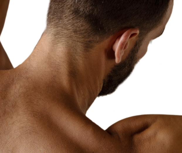 Nahaufnahme des Nackens und Rückens eines Mannes mit dunklem Haar und Bart vor weißem Hintergrund.