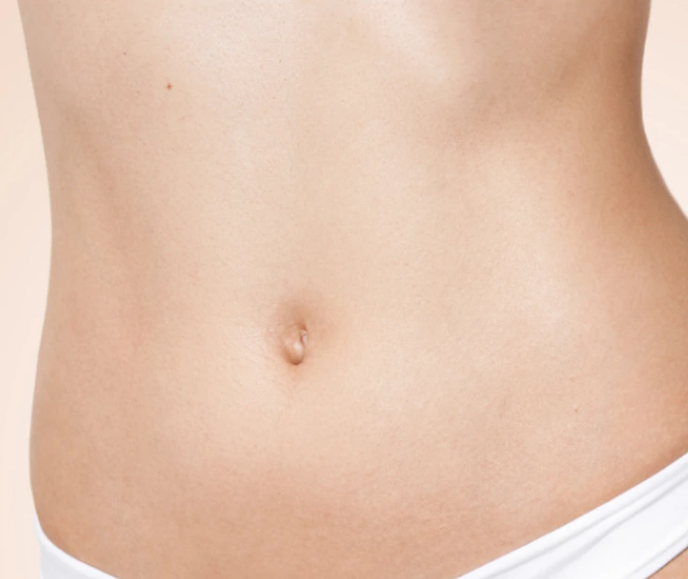 Nahaufnahme eines weiblichen Bauchs mit einem Bauchnabel und weißer Unterwäsche.