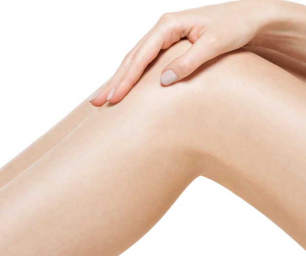 Eine Hand liegt sanft auf einem angewinkelten, glatten Frauenbein vor weißem Hintergrund.