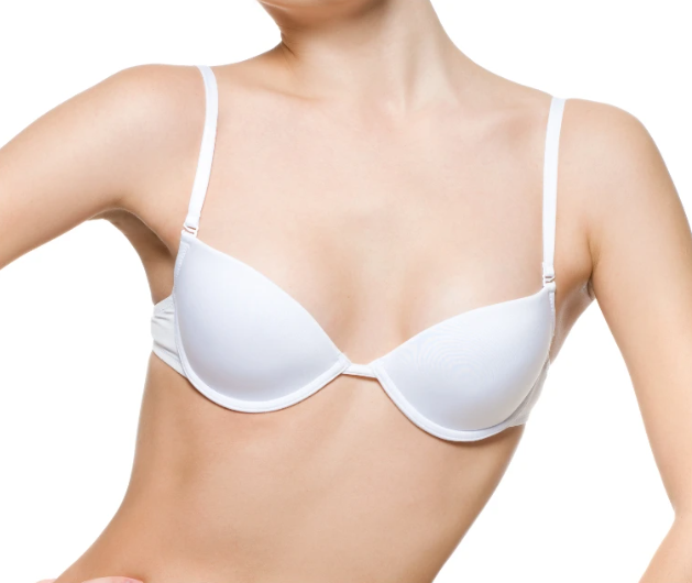 Frau trägt einen weißen Bügel-BH ohne sichtbare Kleidung darüber, Ausschnitt von Hals bis Taille.