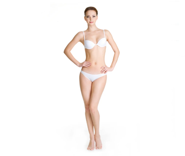 Frau in weißem BH und weißem Slip steht barfuß mit Händen in der Taille vor weißem Hintergrund.