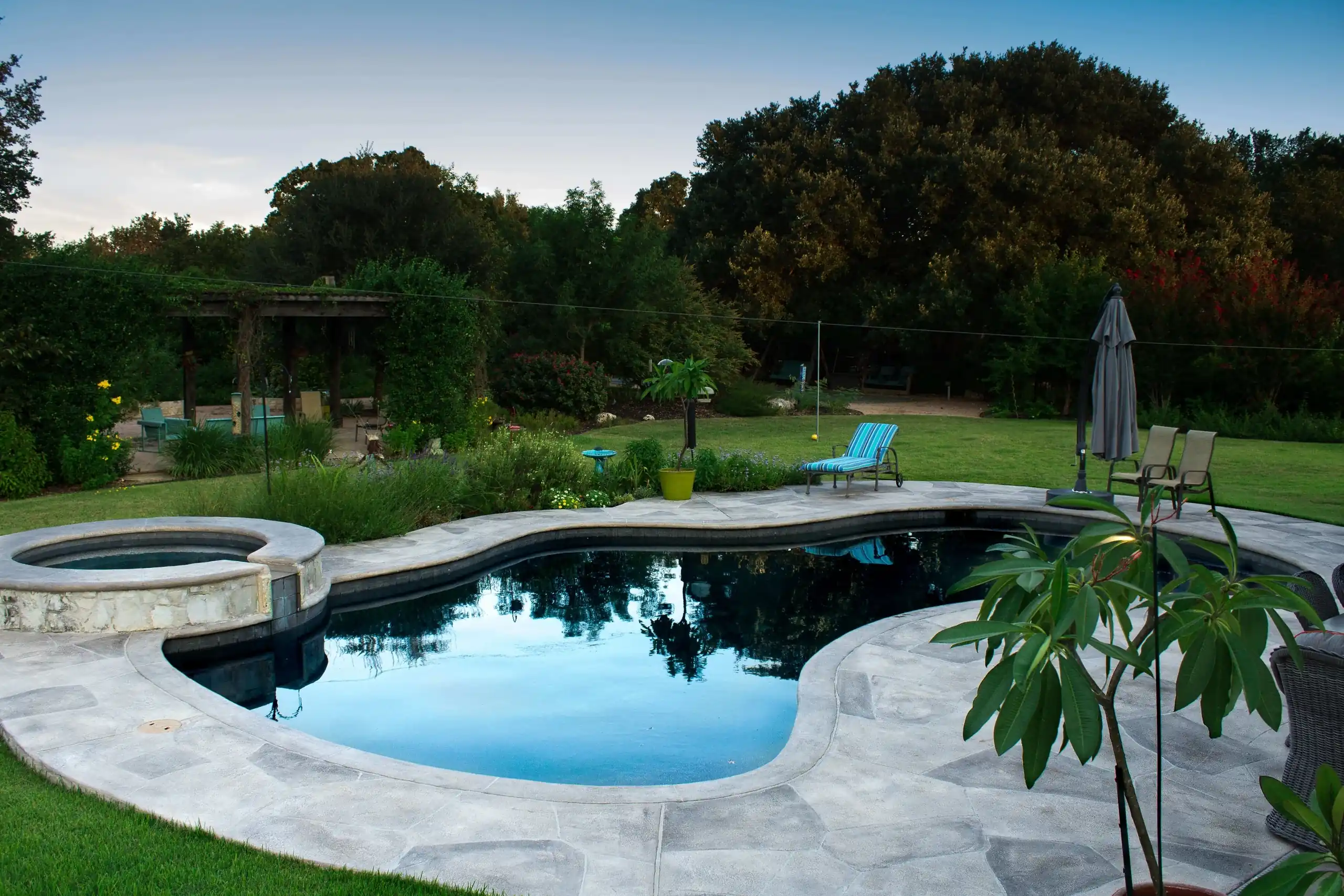 freeform inground pool and spa with light colored concrete pool deck, allied outdoor solutions