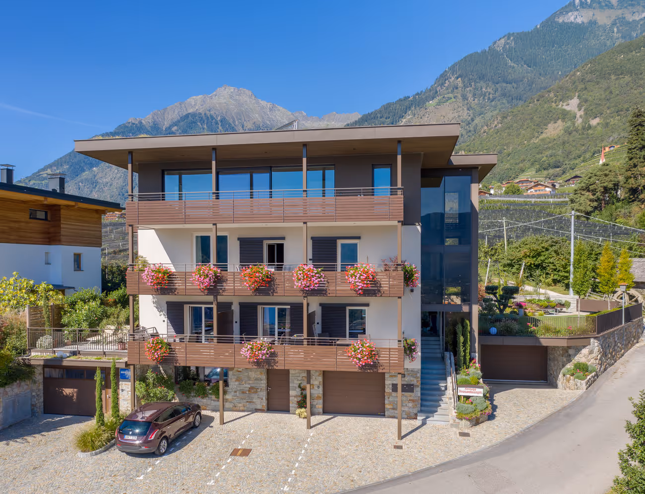 Branding- und Webdesign-Projekt für Steinegg – modernes Apartmenthaus in Südtirol vor Bergkulisse mit blumengeschmückten Balkonen