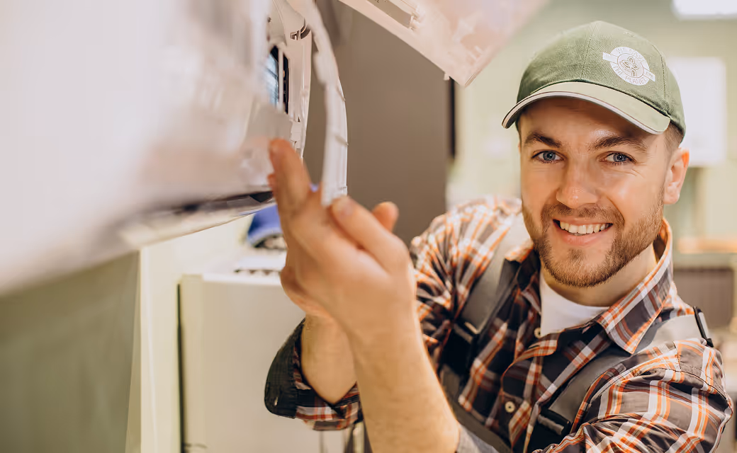 HVAC technician repairing an air conditioning unit and smiling