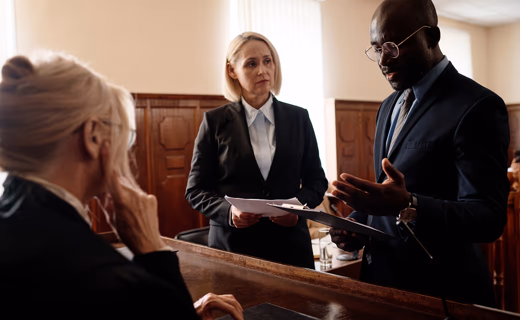 Two lawyers discussing a case with a client in a courtroom setting