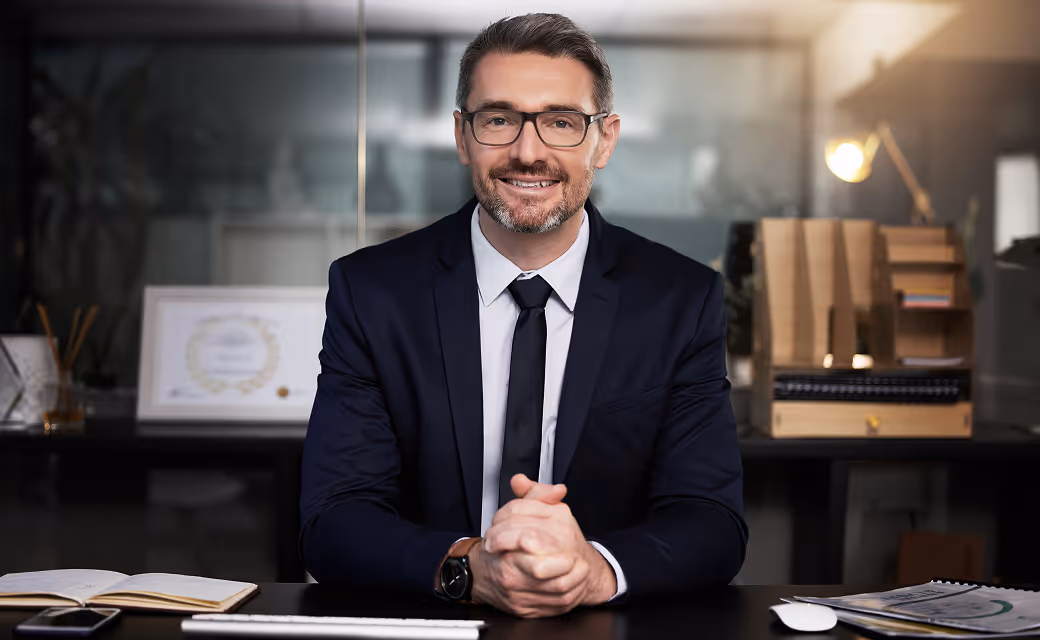 Lawyer in a suit smiling at their desk in an office