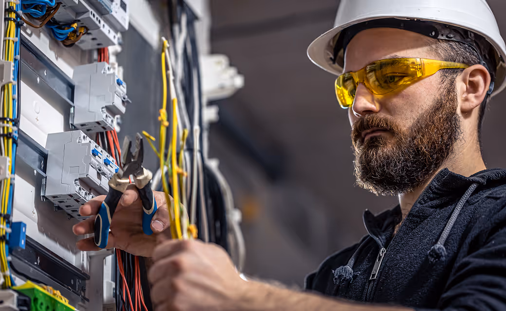 Electrician using pliers to connect wires in a breaker panel