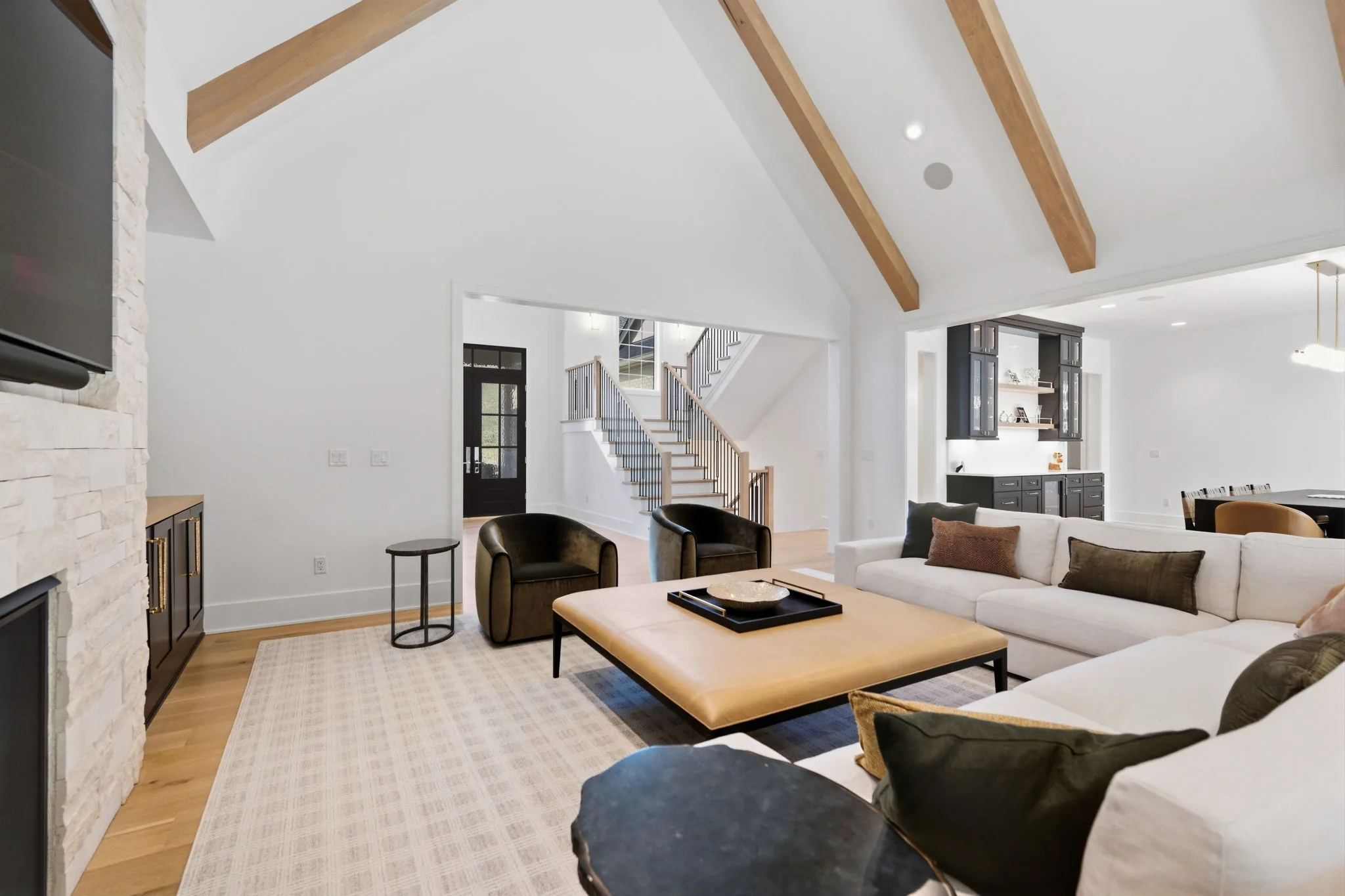 Vaulted great room with exposed wood beams and a stacked-stone fireplace