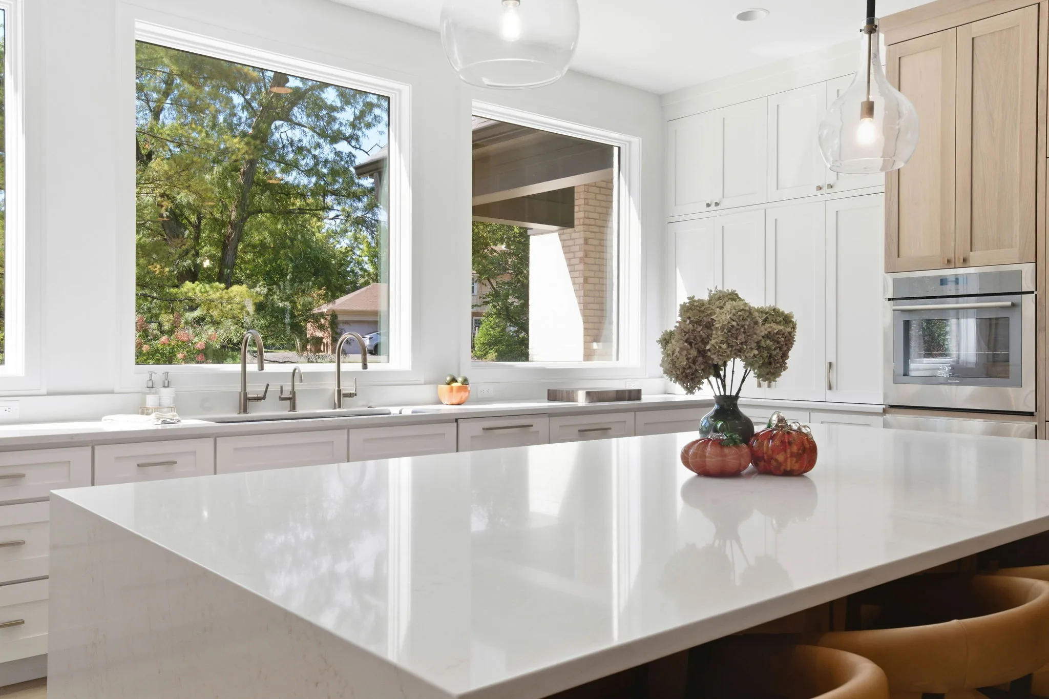 Kitchen island and sink wall with large windows overlooking the trees