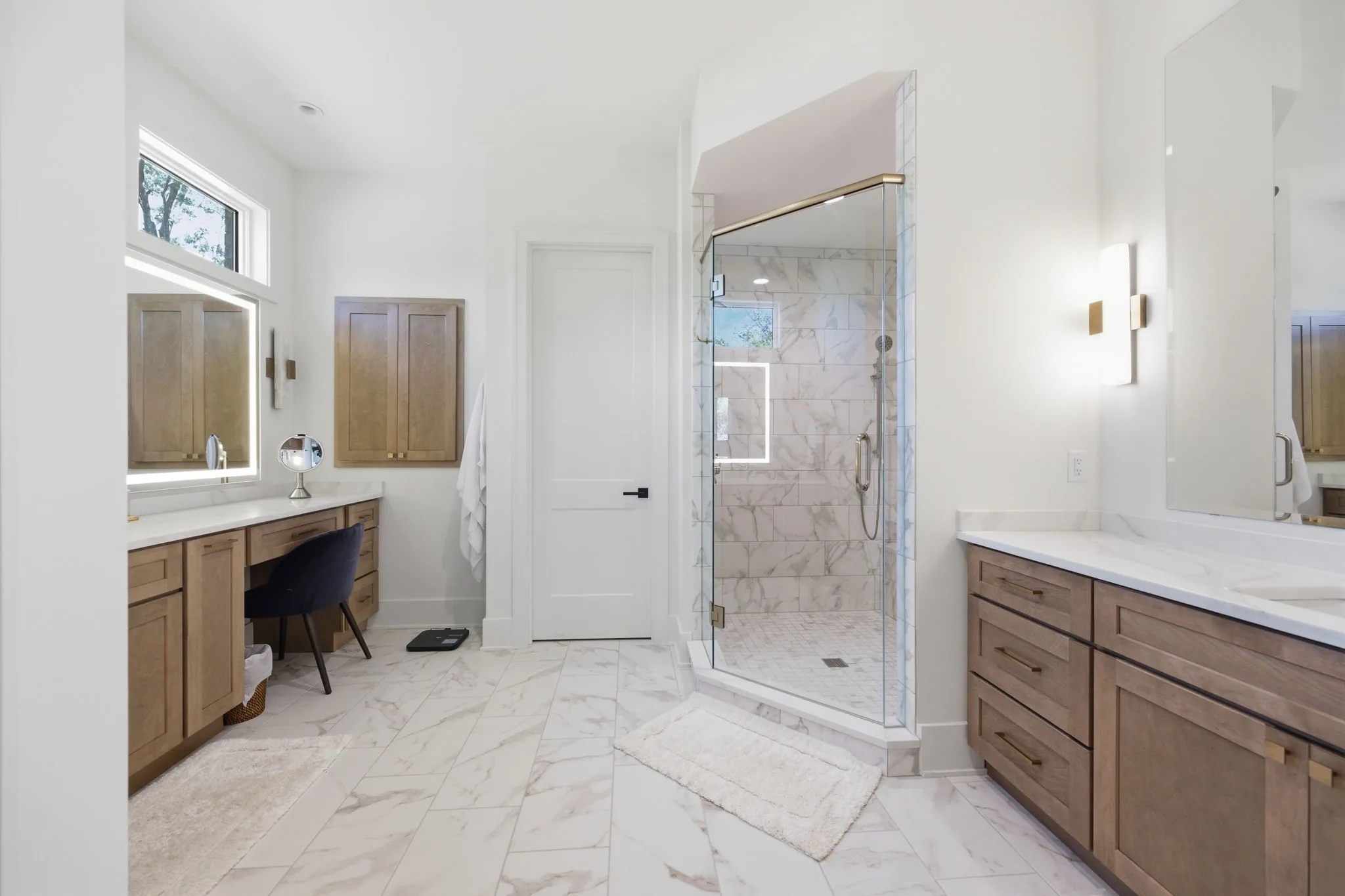 Primary bathroom with a makeup vanity, glass-enclosed shower, and wood vanities