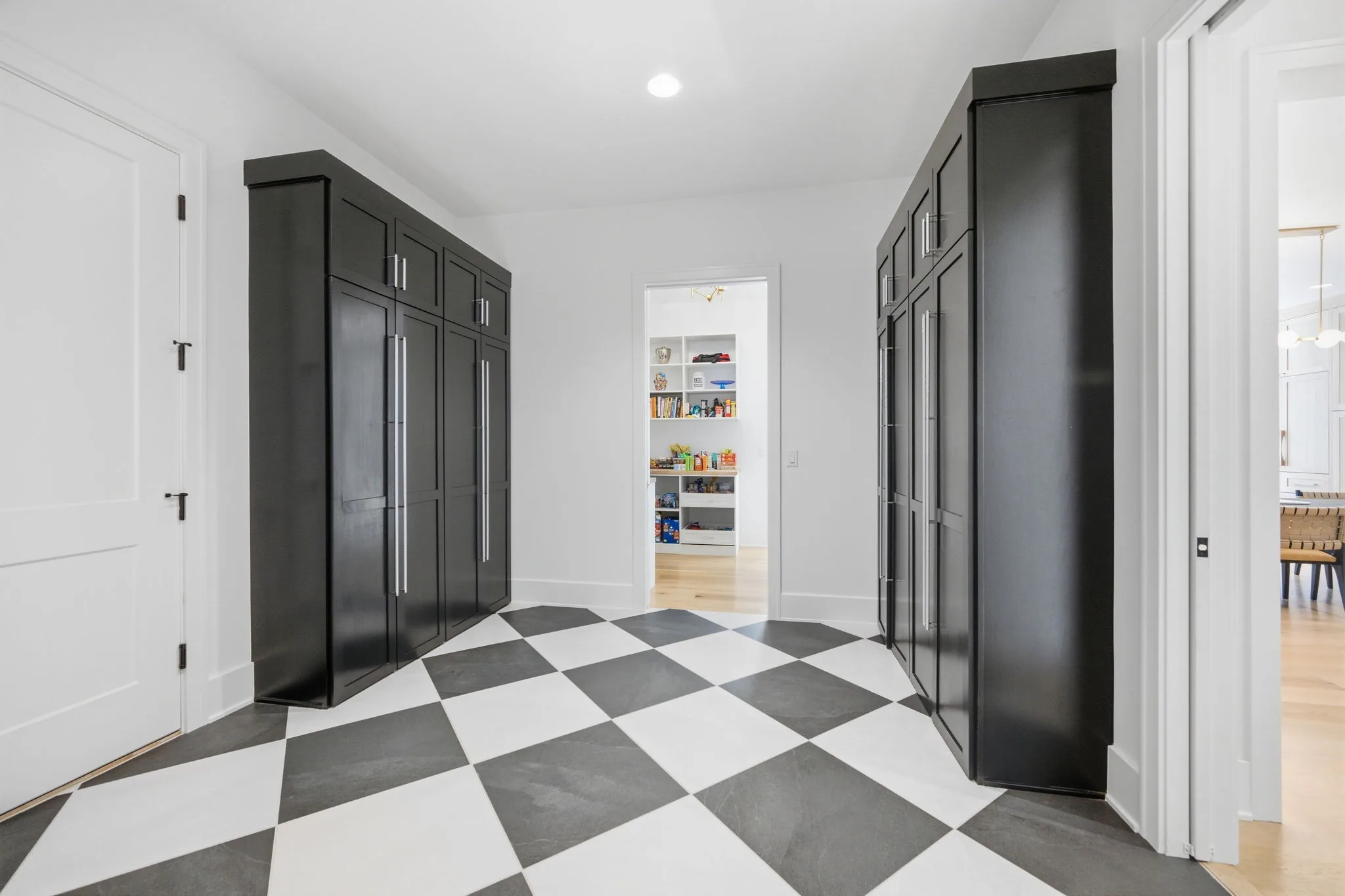 Drop zone with black built-in lockers and a checkerboard tile floor leading to a walk-in pantry