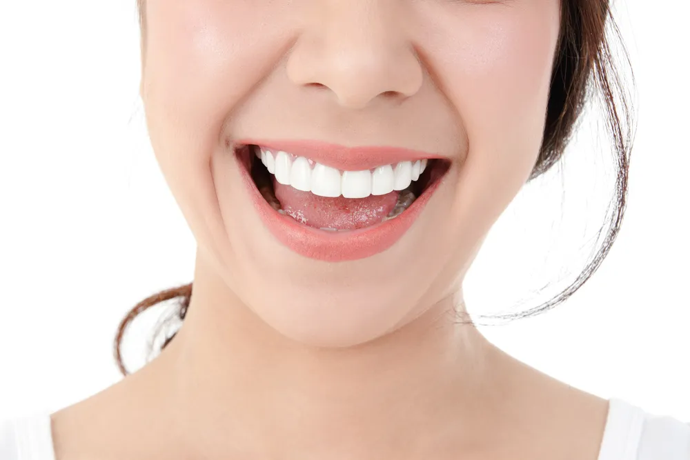 A person holds a dental shade guide featuring various shades of teeth, showcasing the selection for dental procedures.
