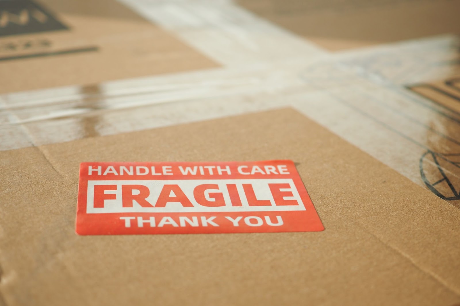 A cardboard box labelled with a "HANDLE WITH CARE, FRAGILE, THANK YOU" sticker.