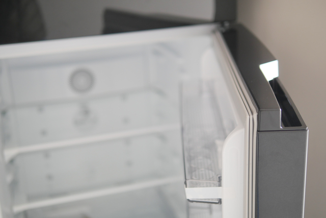 Half open silver fridge with no contents.