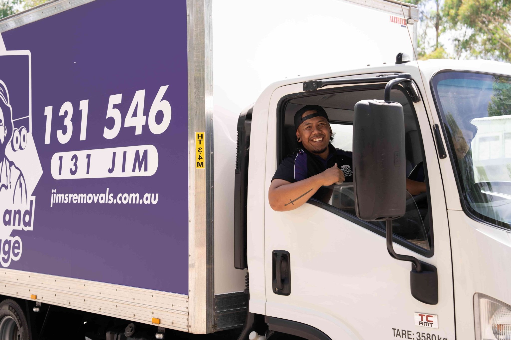 Purple Jim's Removals truck with Jim's Removals mover in the drivers seat.
