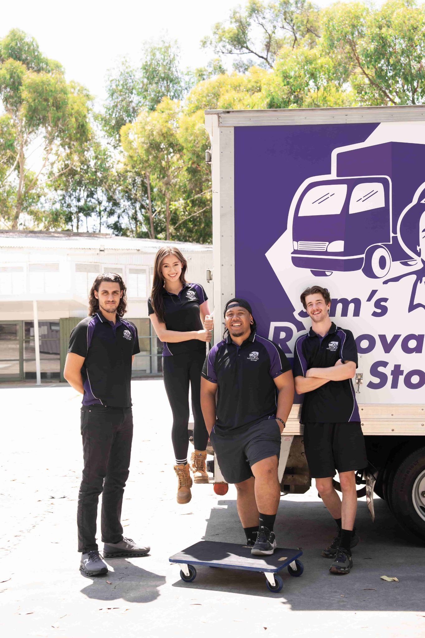 Jim's Removals and Storage team in front of a purple moving truck.