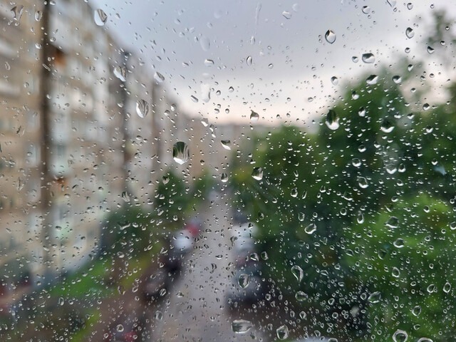 Raindrops on a glass window with a blurry apartment in the background
