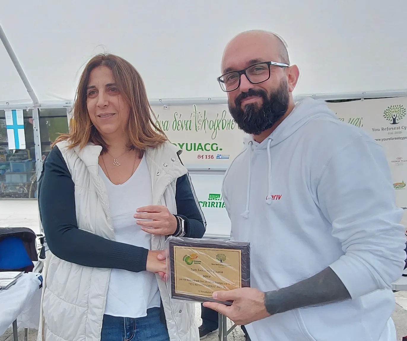 Geo Nicolaidis holding the plaque with a leaf emblem.