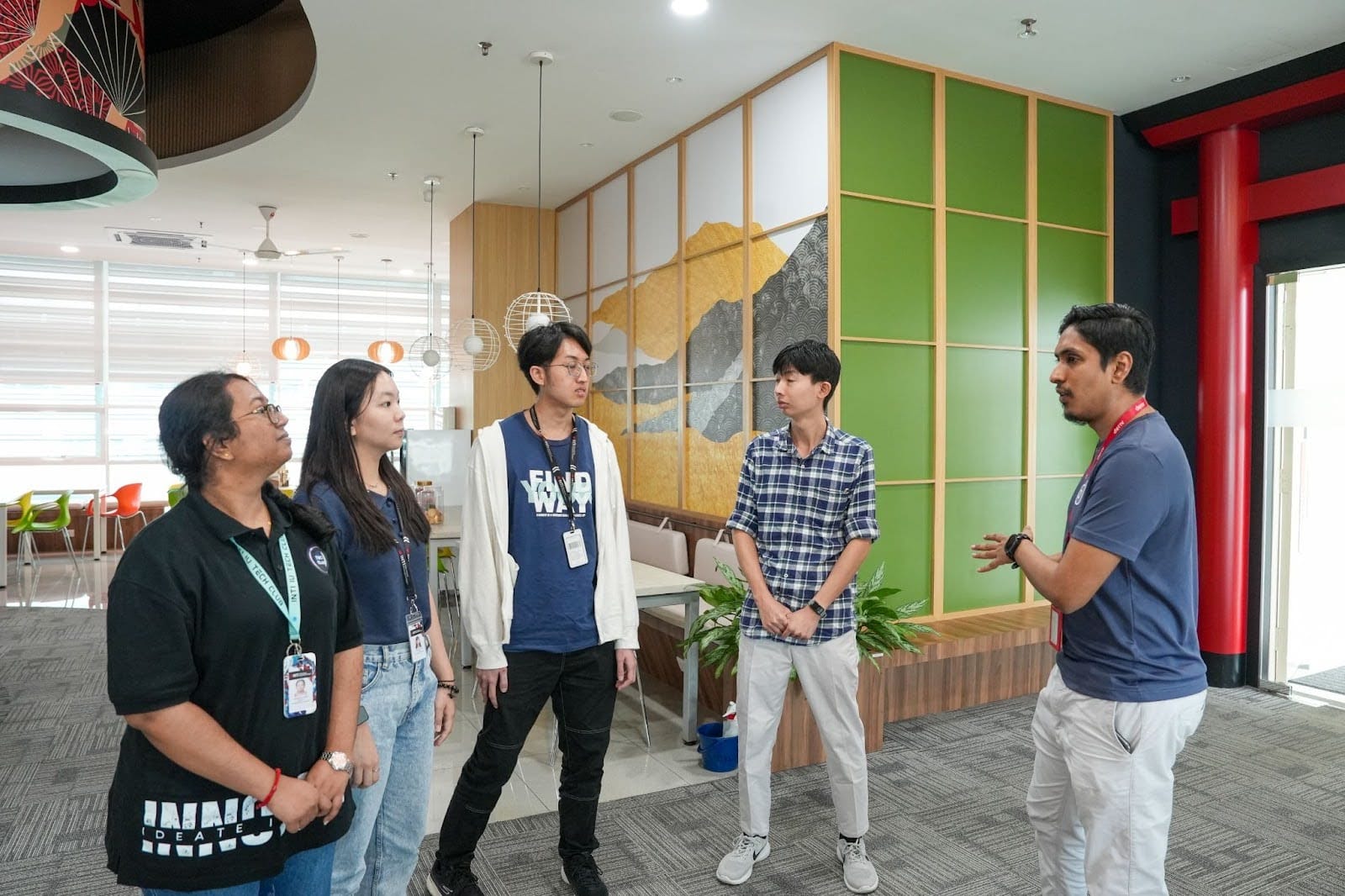 عضو من فريق Deriv يقدم جولة في المكتب لأعضاء جمعية تقنية المعلومات في INTI.