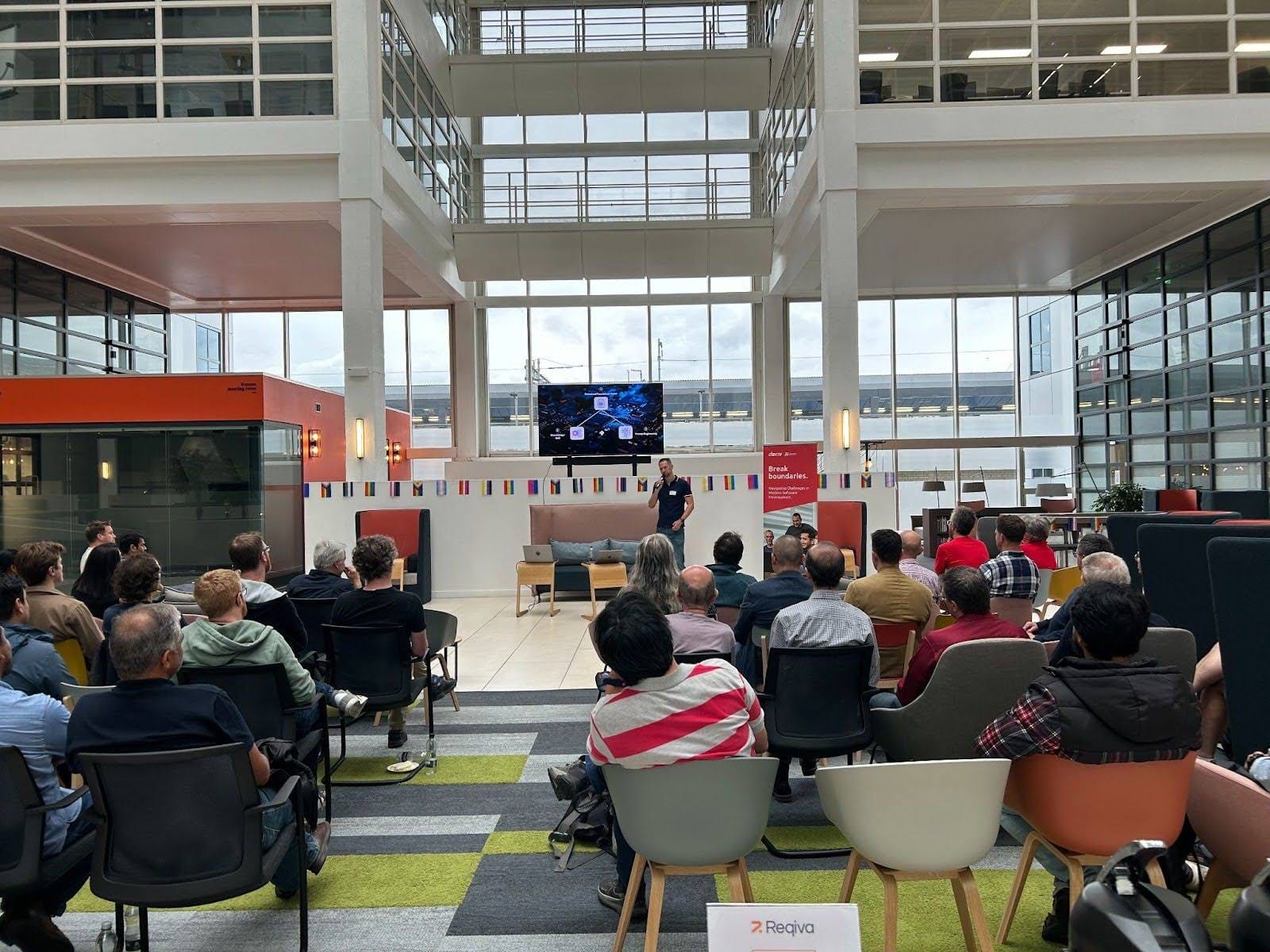 الحاضرون في فعالية Deriv بالمملكة المتحدة، يستمعون بانتباه إلى المتحدث في قاعة حديثة.