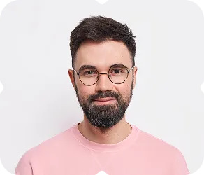 A man with glasses and a beard wearing a pink shirt.
