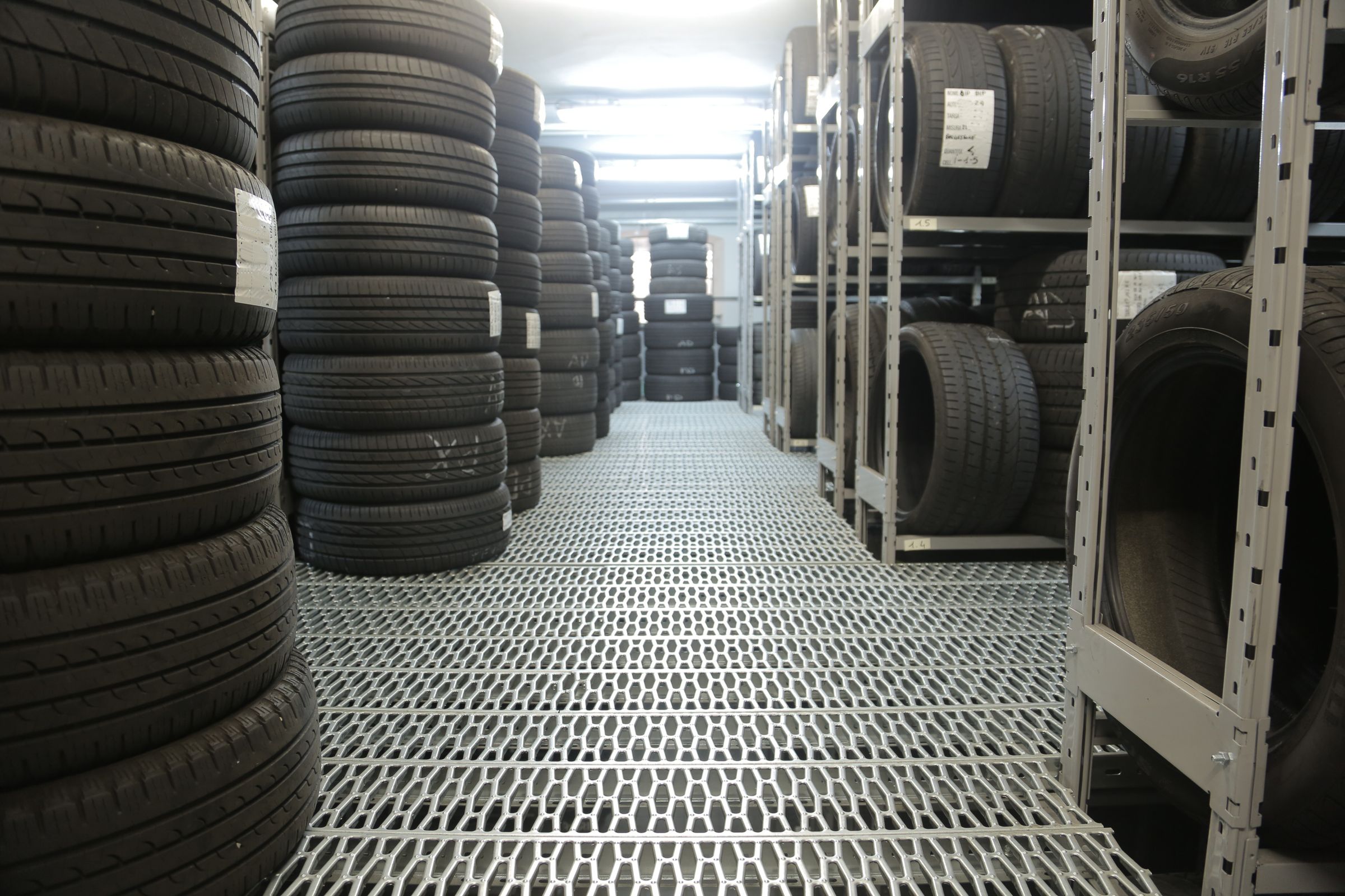 Tyre storage aisle with stacks of car tyres and grey metal shelving