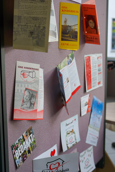 Een informatiebord met historische brochures, flyers en bedankkaartjes van Ons Kinderhuis, tentoongesteld tijdens het jubileum.