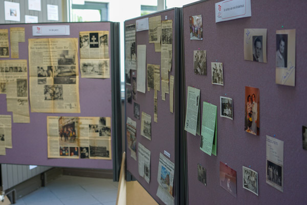 Een tentoonstelling met oude krantenartikelen en foto's toont de geschiedenis van Ons Kinderhuis in een binnenruimte.