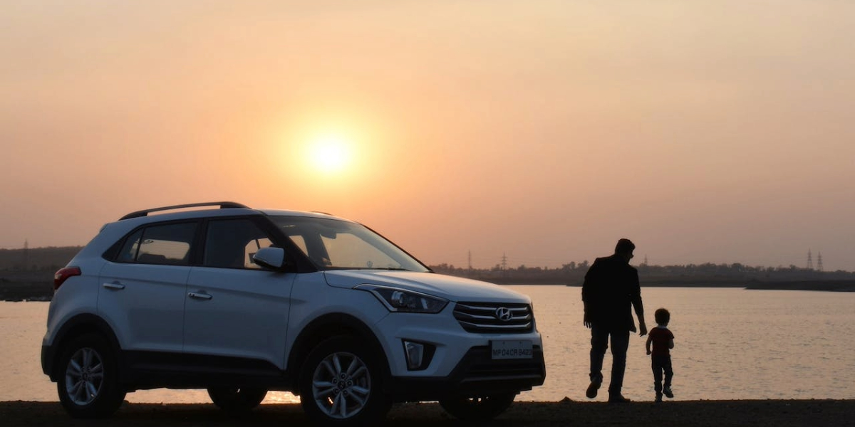 Silhouette of Man and Child Near White Hyundai Tucson SUV during Golden Hour