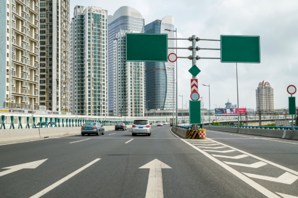 Highway with traffic signs and city buildings.
