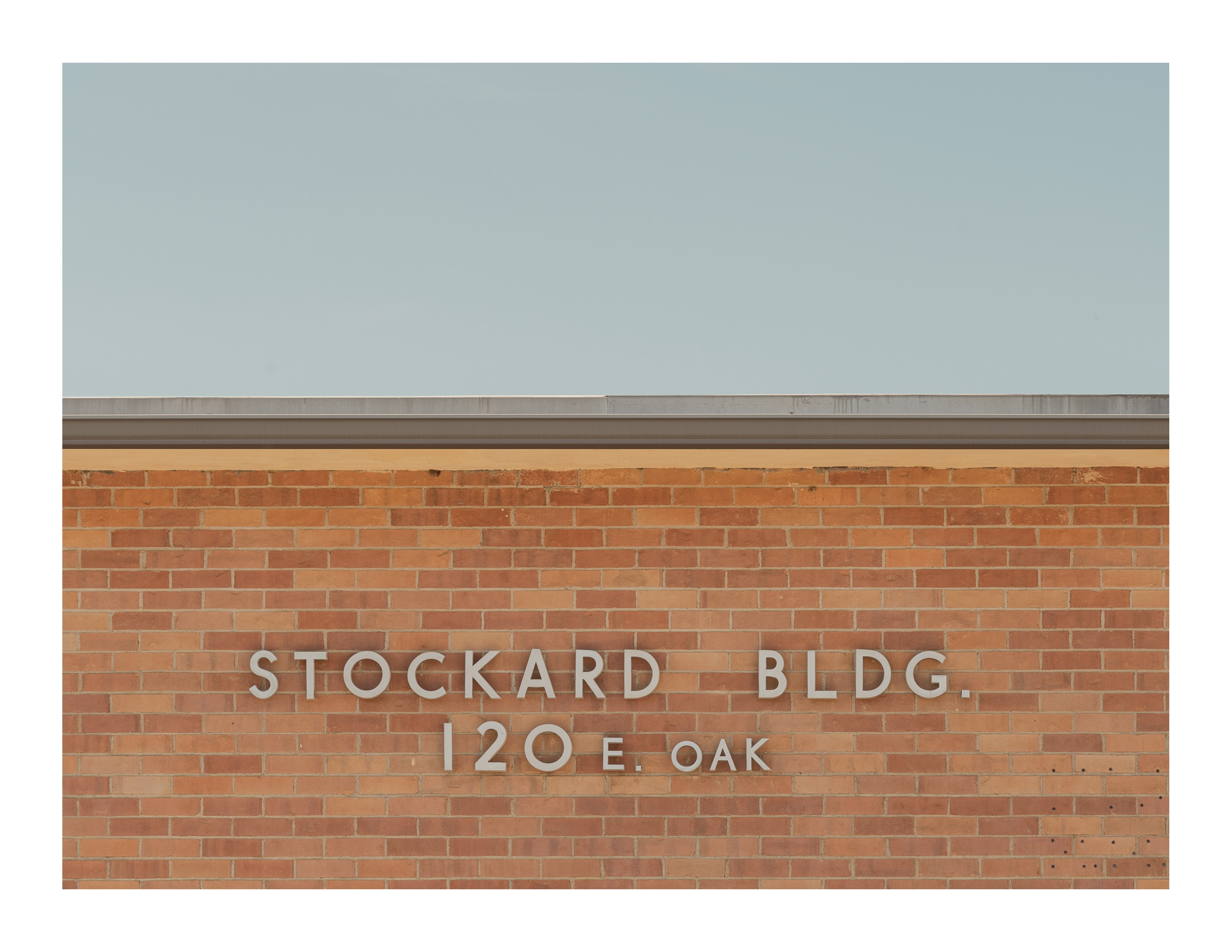Stockard Building sign on red brick wall beneath pale blue sky