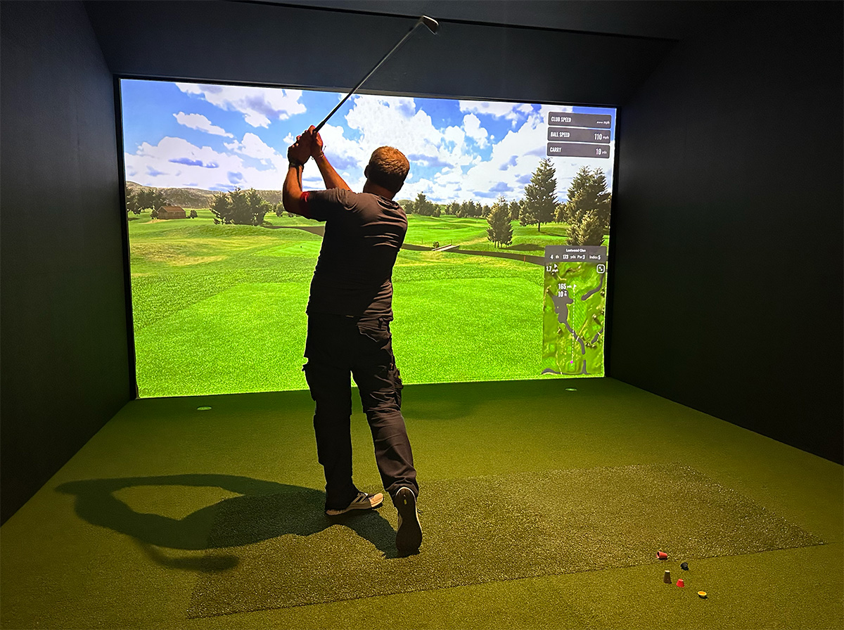 A man finishing a golf swing in a GolfSpace