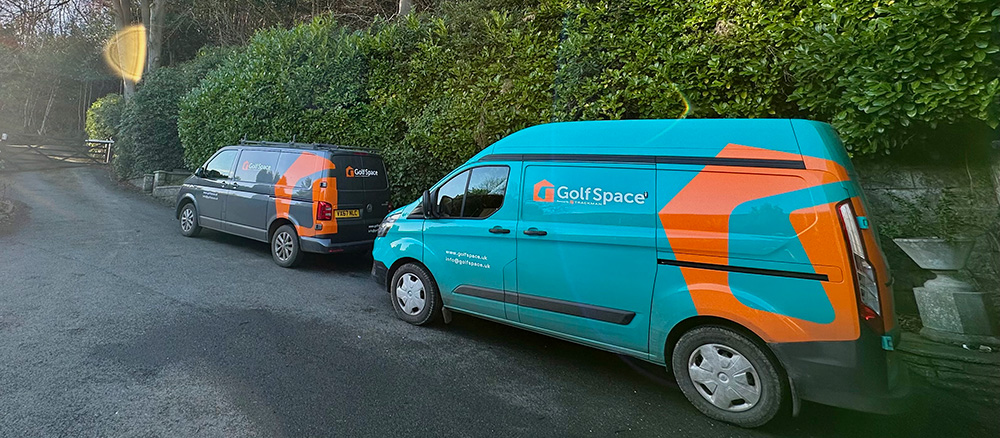 GolfSpace vans parked alongside a high hedge, ready to be unloaded to create a new GolfSpace.