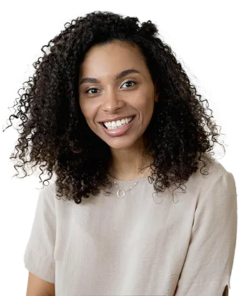 Smiling woman with curly hair wearing a light beige blouse and a silver necklace.