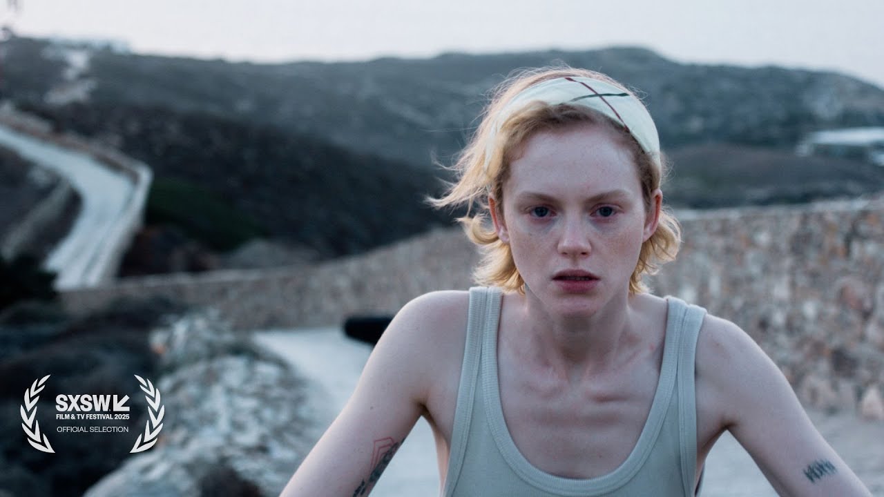 Woman in tank top with headband standing at rocky landscape with forested hills