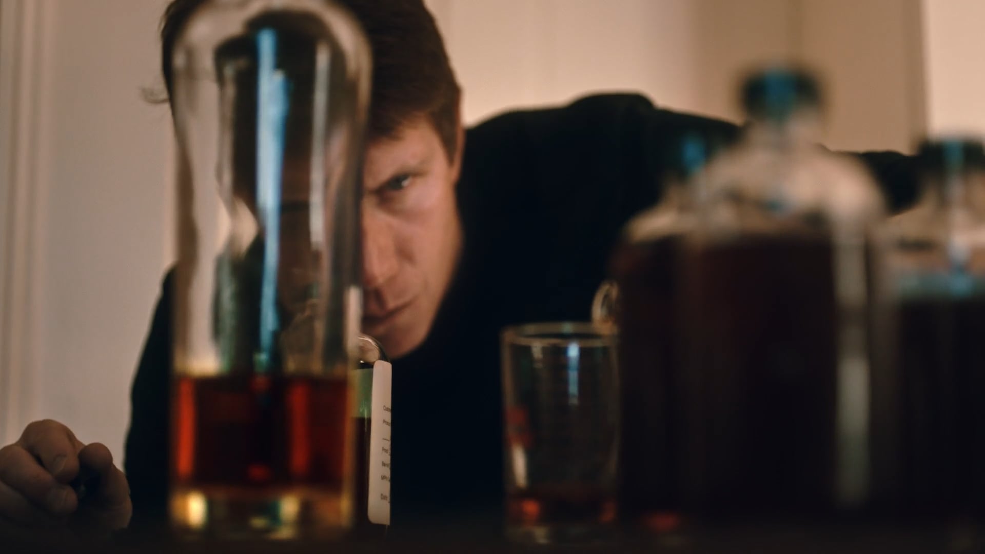 Woman examining red liquid in laboratory test tubes and bottles