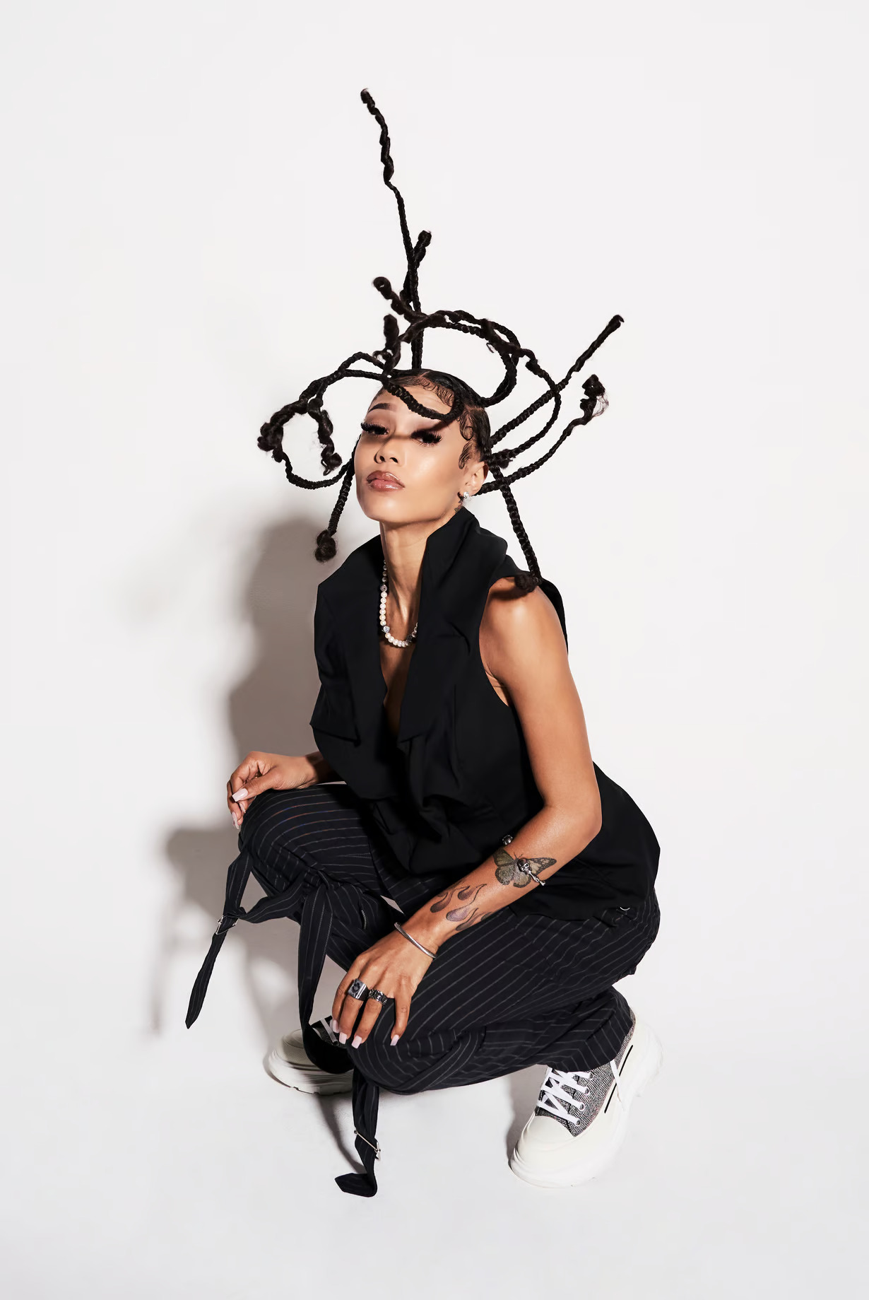 Woman in black outfit with artistic twisted branch headdress and white sneakers