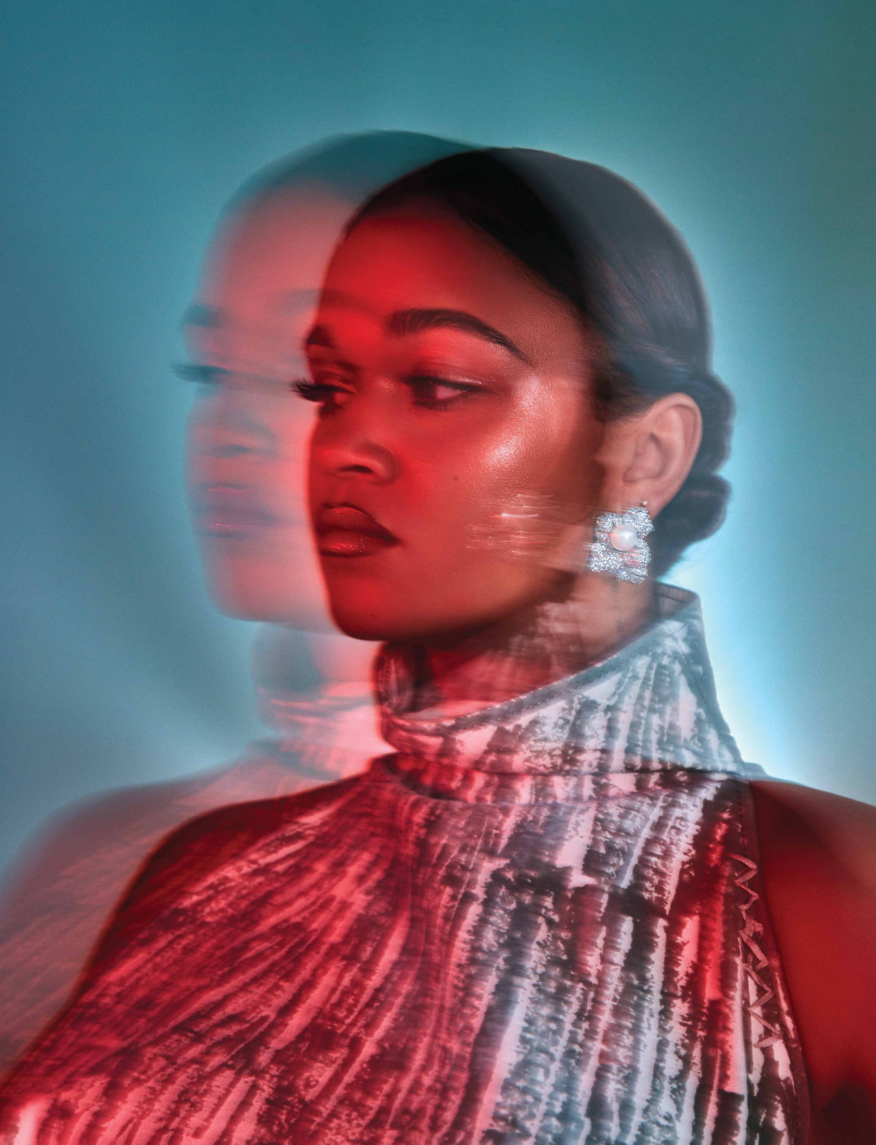 Woman with double exposure effect, red lighting, and sparkly earring against teal background