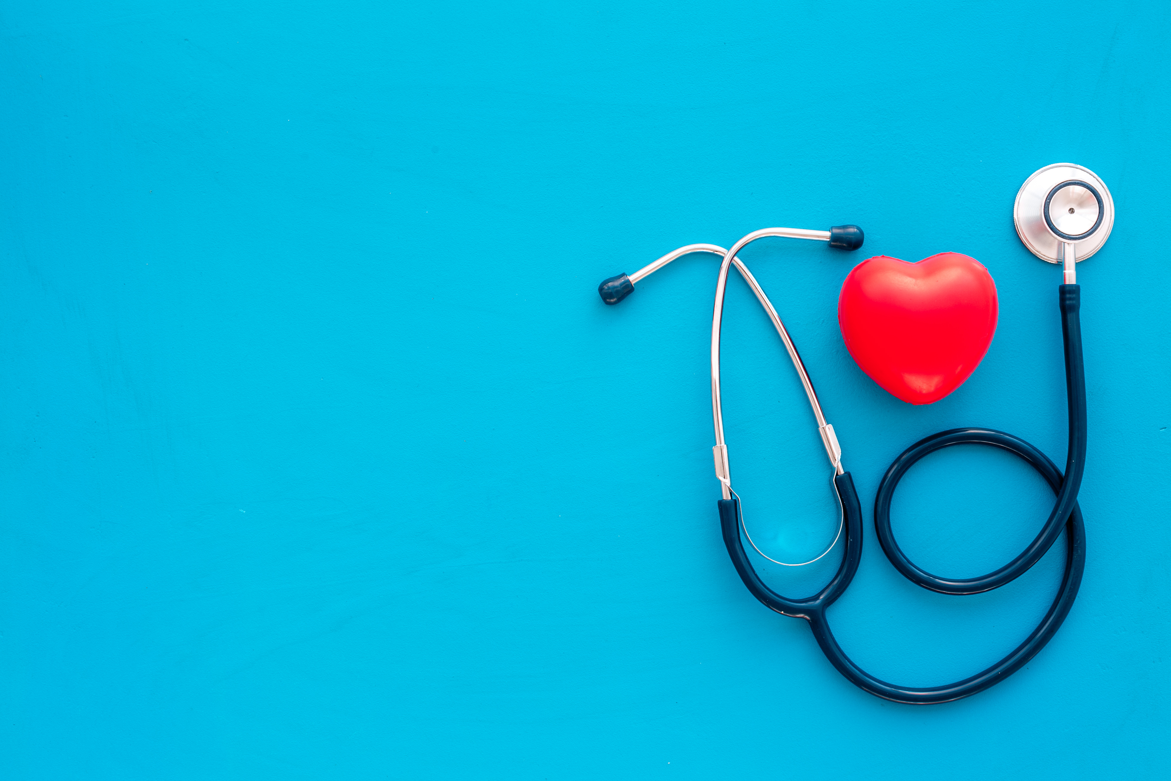 Heart health, health care concept. Stethoscope near rubber heart on blue background top view space for text