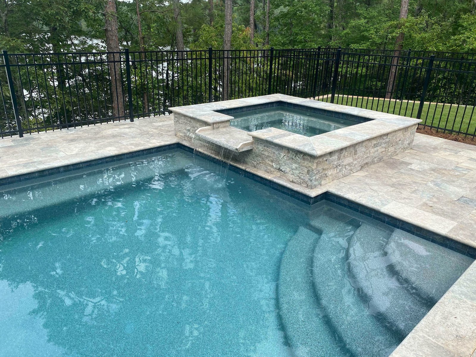 Travertine pavers create a stunning patio surrounding a pool.
