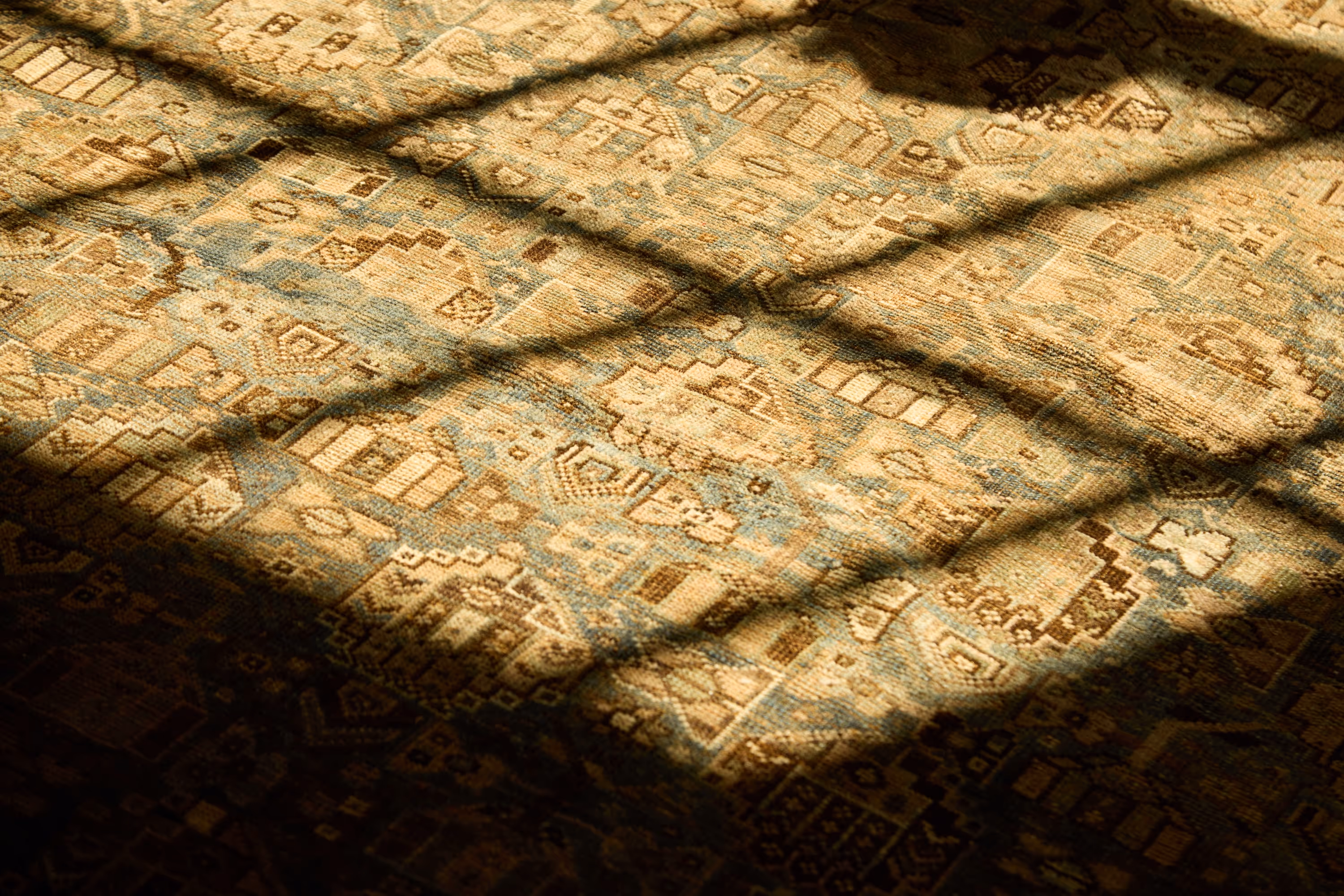 A close-up of a handwoven Moattar rug bathed in golden afternoon light, revealing intricate patternwork and the soulful texture that defines timeless craftsmanship.