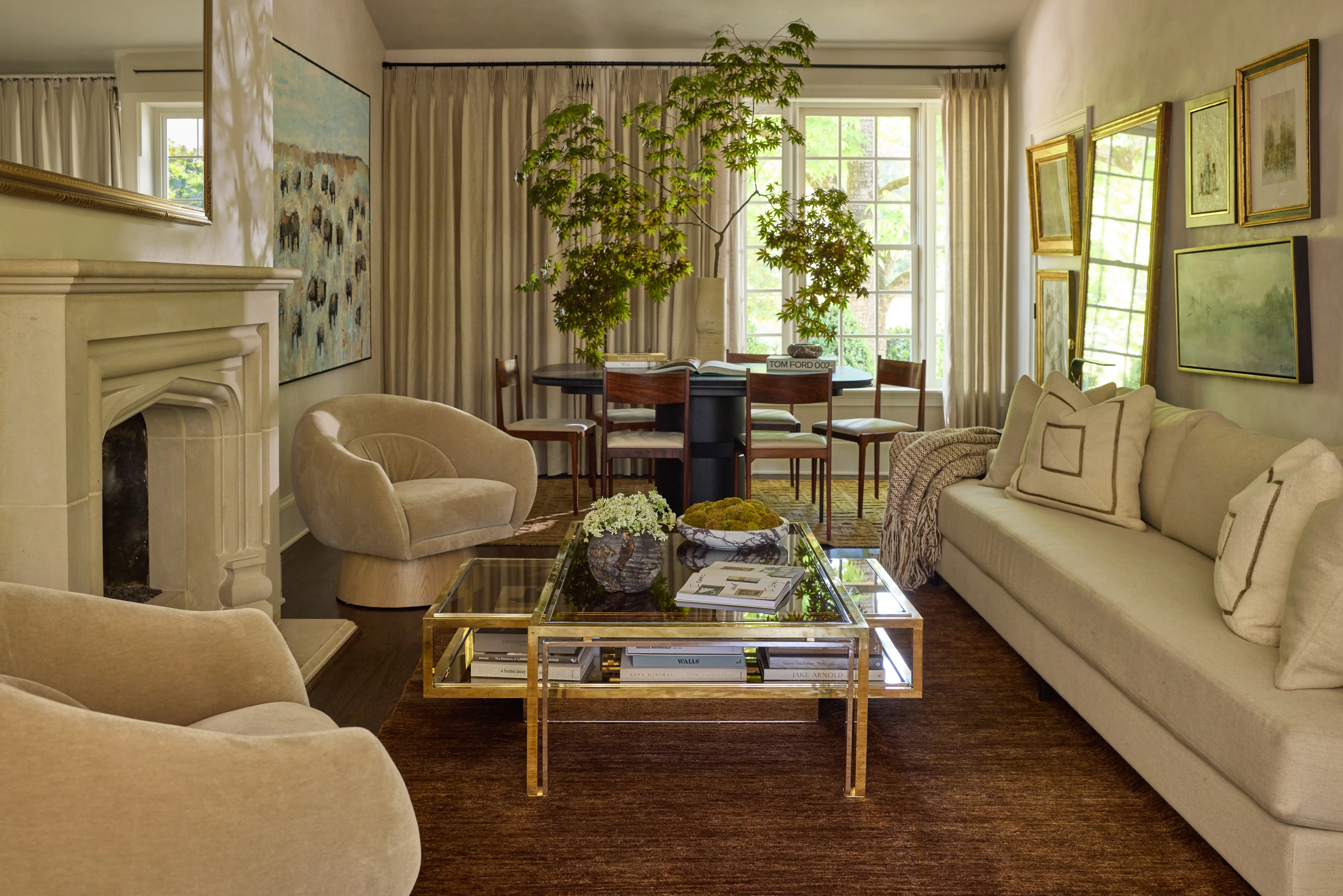 Cozy living room with beige sofa, armchairs, glass coffee table, dining area, and large window with curtains.