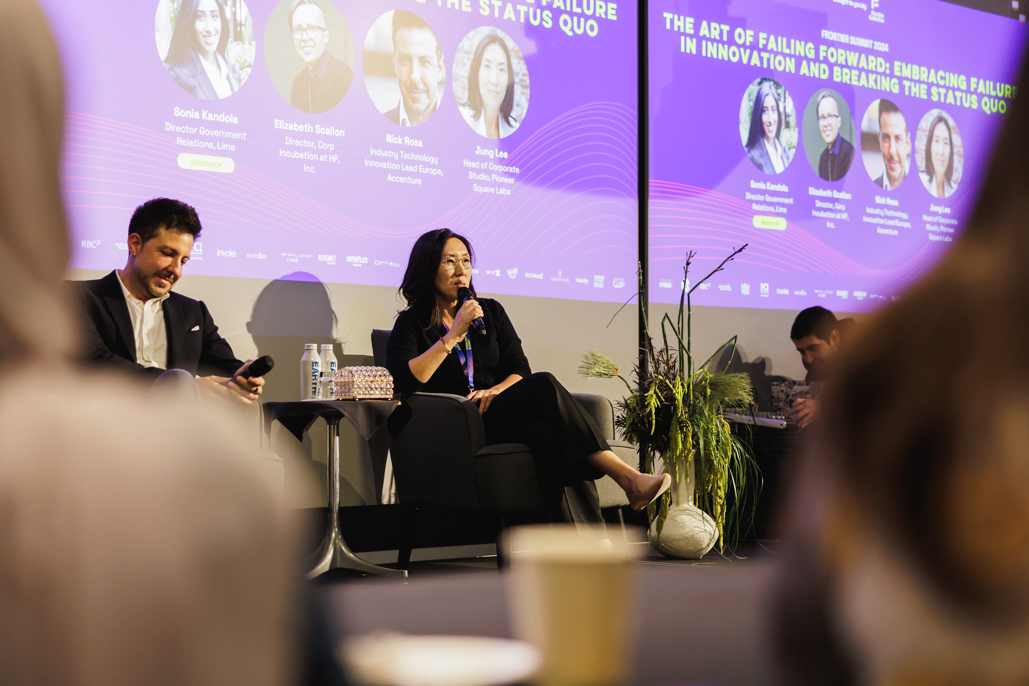 Panellists seated on stage during a session titled The Art of Failing Forward, with speaker headshots projected behind them.