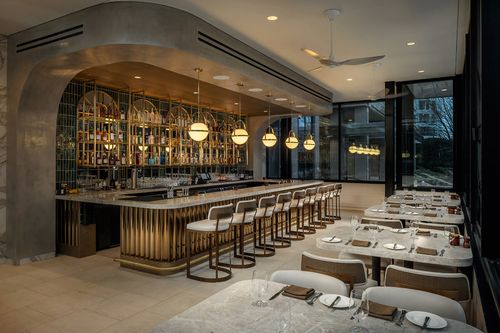 On-site stylish restaurant interior featuring sleek bar, elegant tables and chairs, modern decor, illuminated by warm lighting.