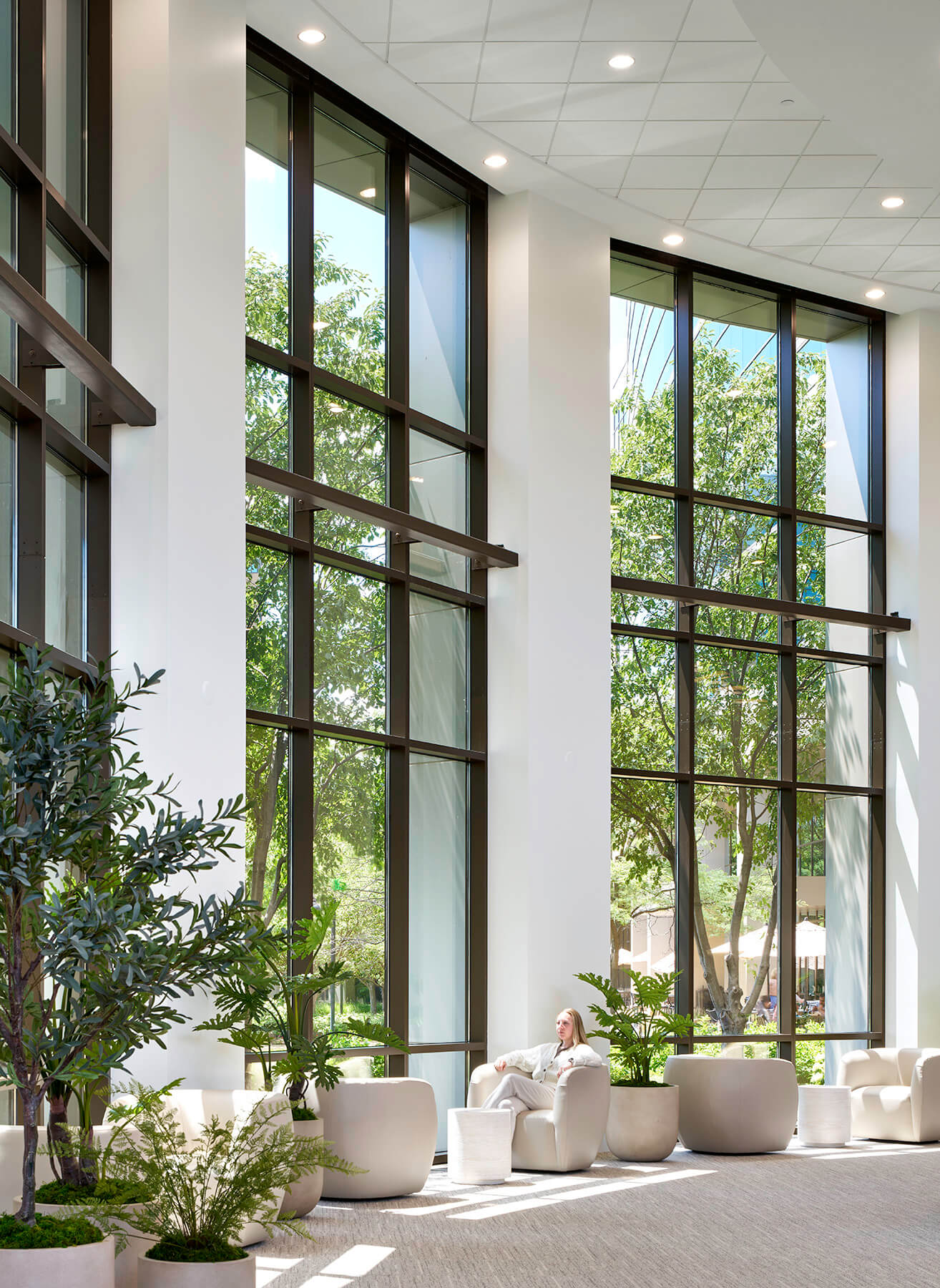 Elegant interior lobby shot with person sitting on couch in front of floor to ceiling windows.