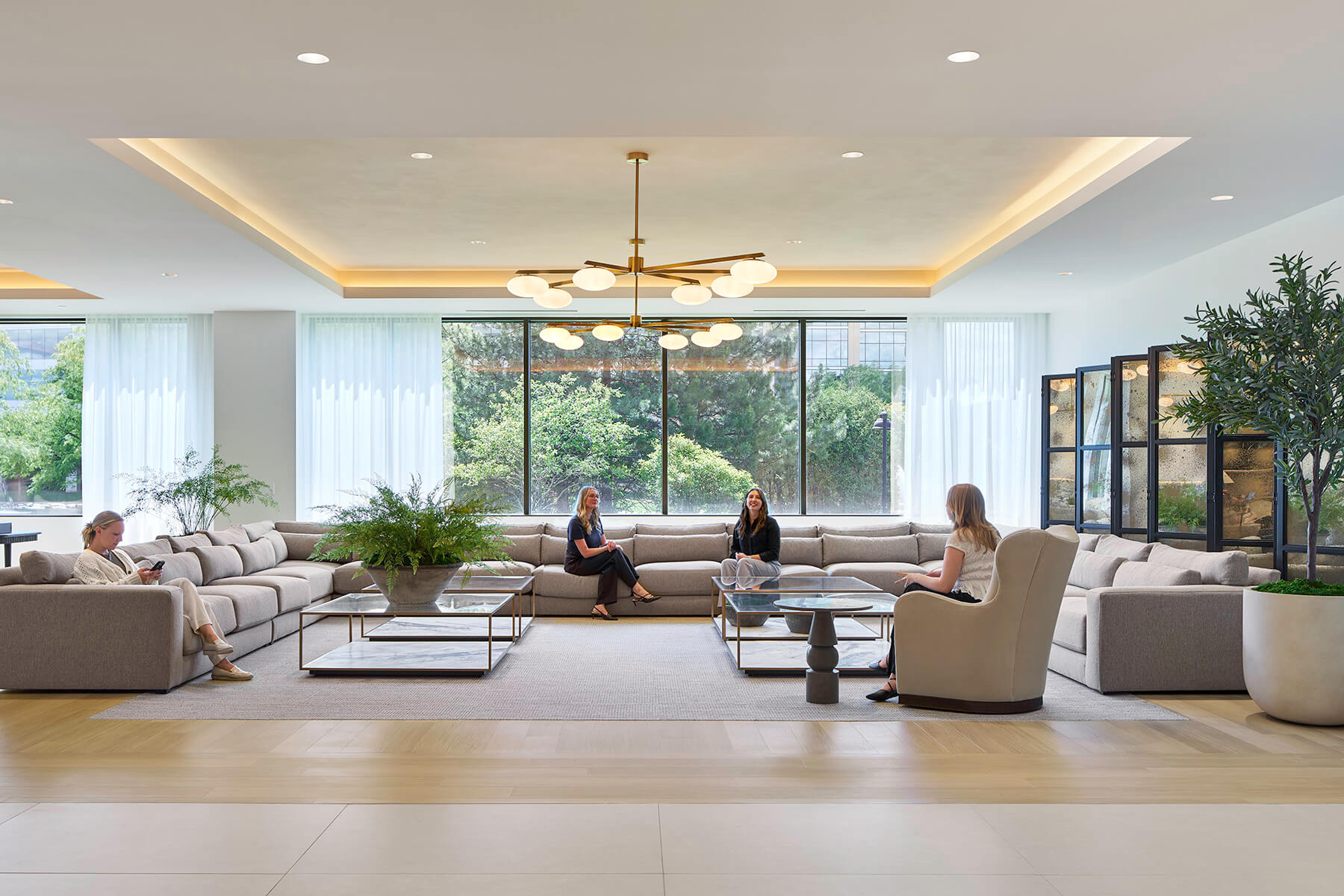 Photo of lobby seating area with soft gray couches and floor to ceiling windows.