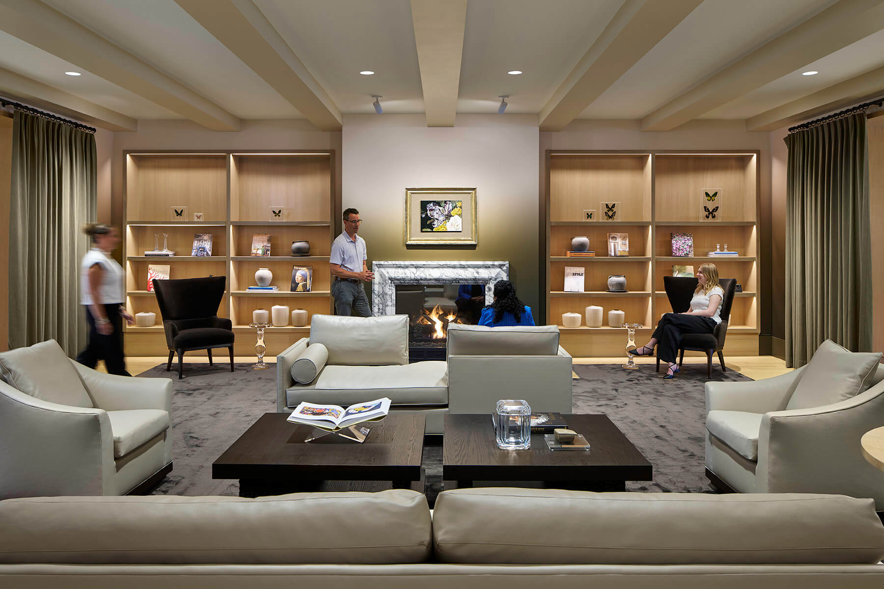 Cozy and warm interior shot of couches and library seating with fireplace.