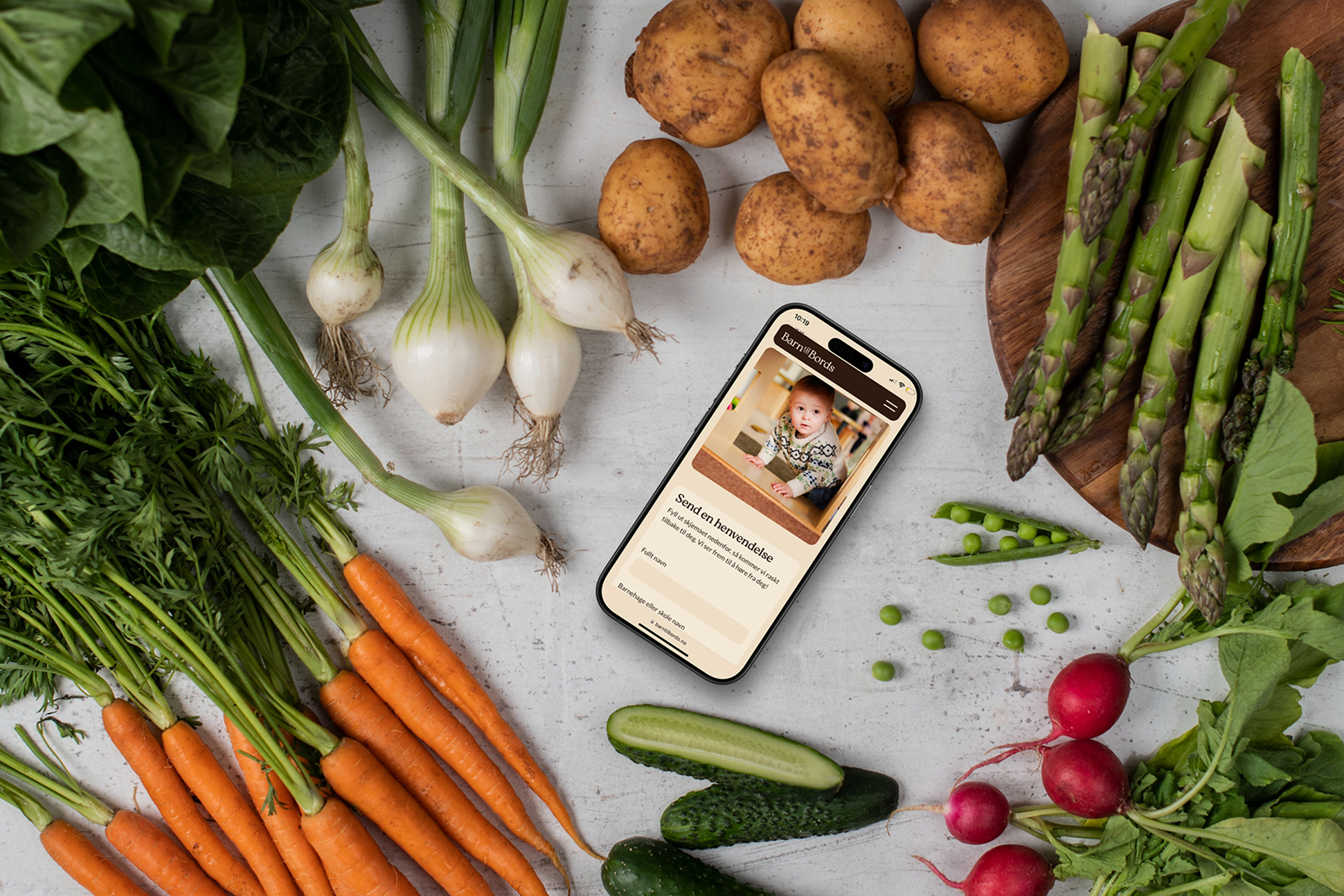 Barn til Bords on a phone surrounded by vegetables